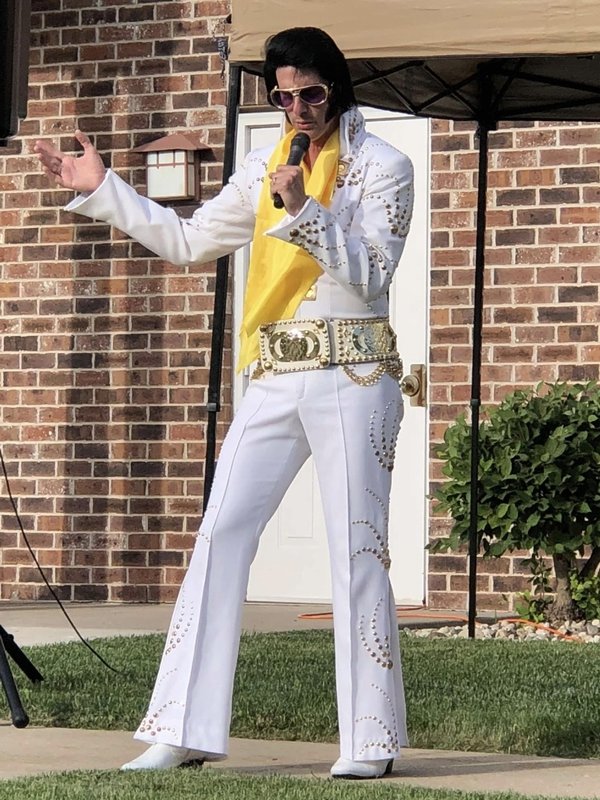 Alan Graveen performing as Elvis in white jumpsuit with yellow scarf